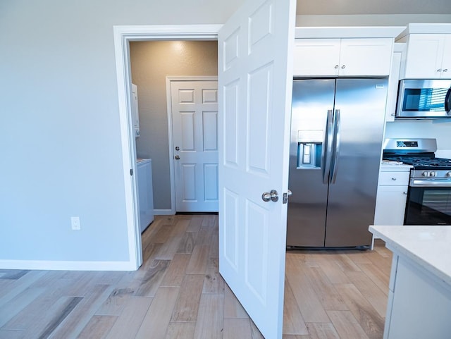 873 Beaver Pond Loop, Madera, CA 93636 - kitchen with stainless steel appliances, white cabinetry, light countertops, and light wood finished floors