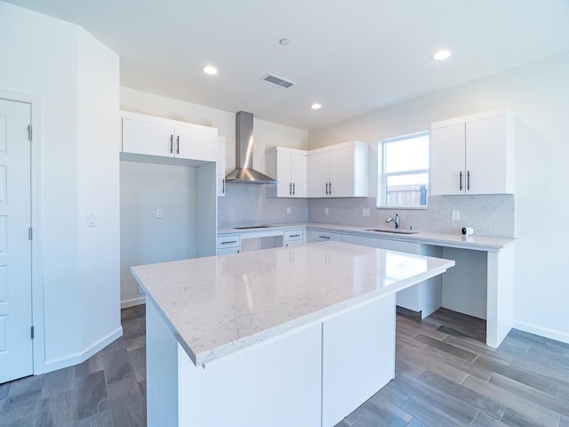 878 Beaver Pond Loop, Madera, CA 93636 - kitchen featuring wall chimney exhaust hood, light stone counters, a sink, backsplash, and recessed lighting