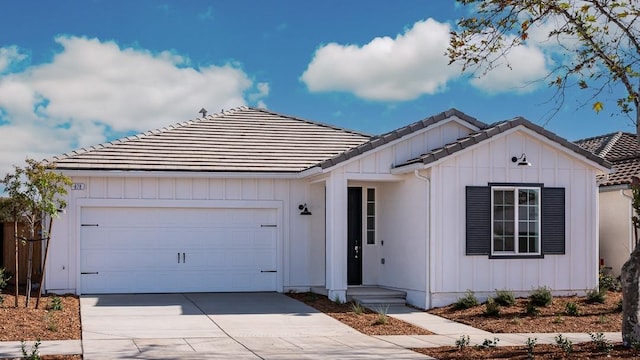 878 Beaver Pond Loop, Madera, CA 93636 - view of front of home featuring concrete driveway, a tiled roof, board and batten siding, and an attached garage