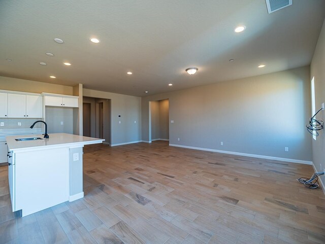 917 Beaver Pond Loop, Madera, CA 93636 - kitchen with a sink, light countertops, white cabinetry, light wood-type flooring, and a center island with sink