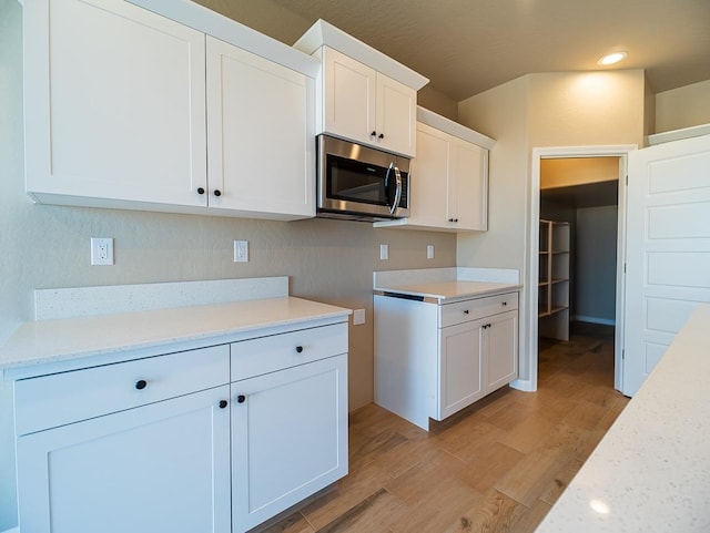 917 Beaver Pond Loop, Madera, CA 93636 - kitchen with stainless steel microwave, light wood-style flooring, white cabinetry, and recessed lighting