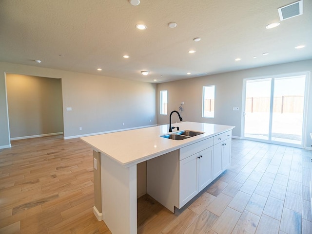 917 Beaver Pond Loop, Madera, CA 93636 - kitchen featuring a sink, light wood-style floors, an island with sink, white cabinets, and light countertops