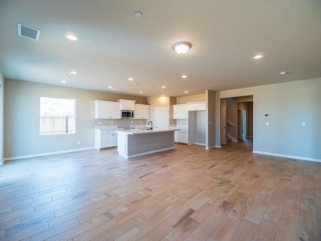 917 Beaver Pond Loop, Madera, CA 93636 - kitchen with stainless steel microwave, open floor plan, a kitchen island with sink, a sink, and baseboards