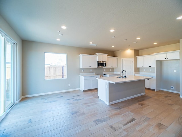 917 Beaver Pond Loop, Madera, CA 93636 - kitchen with stainless steel microwave, a sink, baseboards, a kitchen island with sink, and recessed lighting