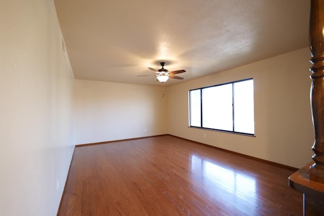 empty room with baseboards, wood finished floors, a ceiling fan, and a textured ceiling