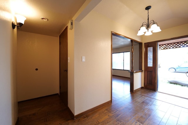 foyer featuring a chandelier, dark wood finished floors, and baseboards