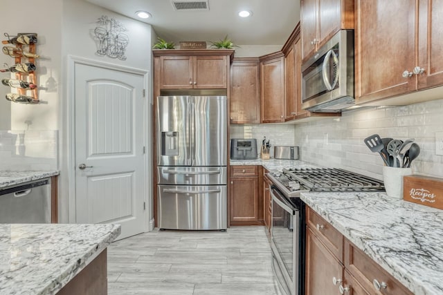 716 Mesa Dr S, Madera, CA 93636 - kitchen with stainless steel appliances, light stone counters, decorative backsplash, recessed lighting, and brown cabinetry