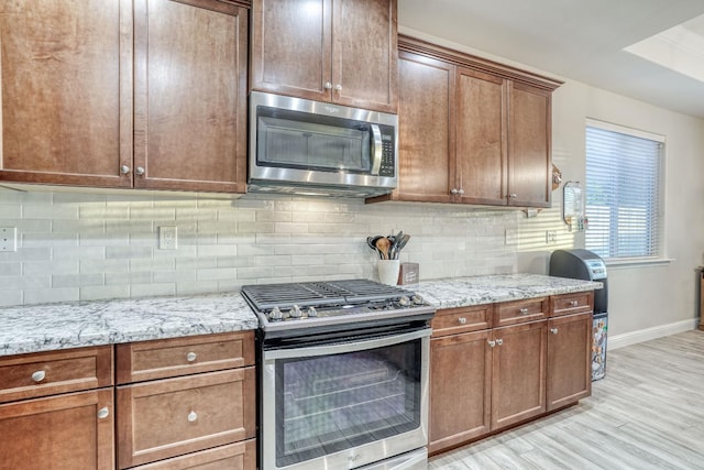 716 Mesa Dr S, Madera, CA 93636 - kitchen featuring appliances with stainless steel finishes, baseboards, light stone countertops, light wood finished floors, and decorative backsplash