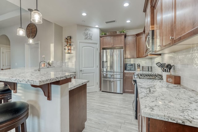 716 Mesa Dr S, Madera, CA 93636 - kitchen featuring stainless steel appliances, a kitchen breakfast bar, tasteful backsplash, light stone countertops, and recessed lighting