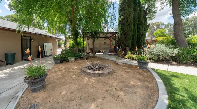 view of yard featuring a fire pit and a patio