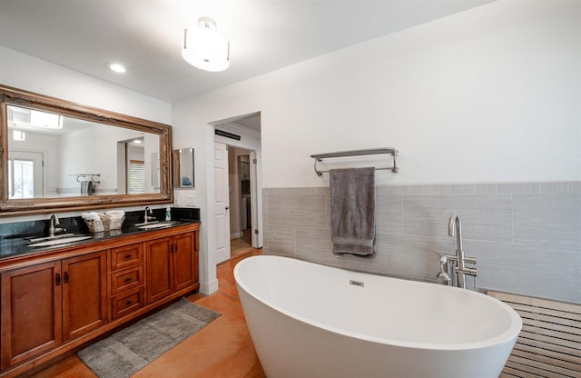 bathroom with a freestanding bath, double vanity, and tile walls
