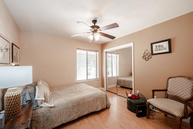 bedroom featuring light wood-type flooring, a closet, ceiling fan, and baseboards