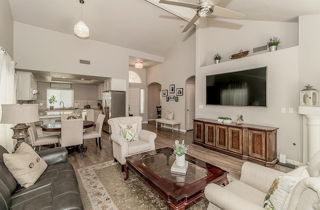 1073 E Pennsylvania Ave, Fresno, CA 93720 - living area featuring arched walkways, a ceiling fan, dark wood-type flooring, high vaulted ceiling, and baseboards