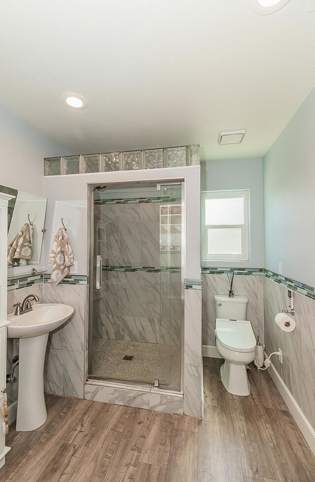 1073 E Pennsylvania Ave, Fresno, CA 93720 - bathroom featuring tile walls, toilet, wood finished floors, a shower stall, and a wainscoted wall