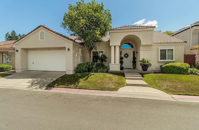 1073 E Pennsylvania Ave, Fresno, CA 93720 - mediterranean / spanish-style home featuring stucco siding, a tiled roof, an attached garage, and a front yard