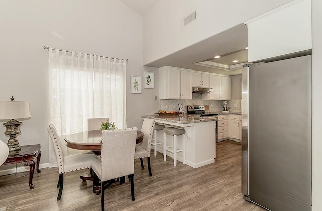 1073 E Pennsylvania Ave, Fresno, CA 93720 - dining area featuring light wood finished floors, a raised ceiling, a high ceiling, baseboards, and recessed lighting