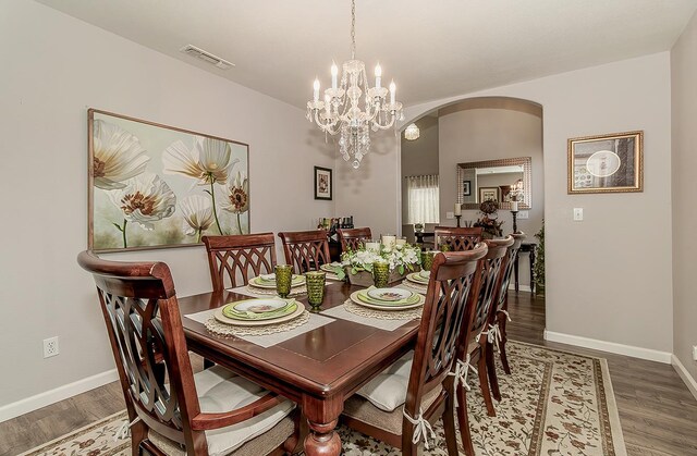 1073 E Pennsylvania Ave, Fresno, CA 93720 - dining space featuring arched walkways, wood finished floors, a chandelier, and baseboards