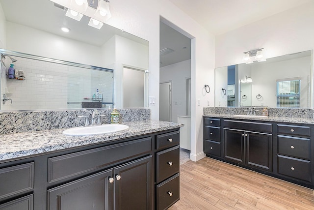 6772 E Ramona Way, Fresno, CA 93727 - bathroom with a stall shower, wood finished floors, and two vanities