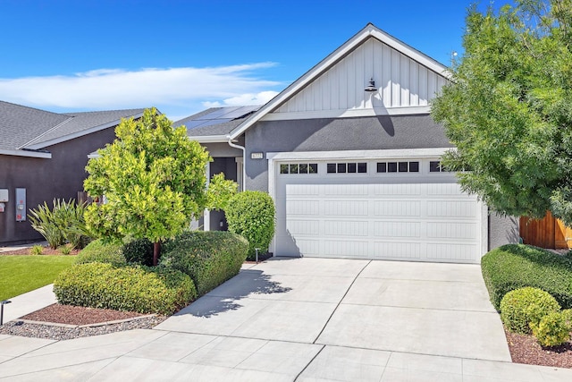 6772 E Ramona Way, Fresno, CA 93727 - view of front of house featuring board and batten siding, solar panels, concrete driveway, a garage, and stucco siding