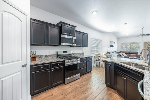 6772 E Ramona Way, Fresno, CA 93727 - kitchen with stainless steel appliances, a sink, light stone countertops, open floor plan, and light wood-style floors