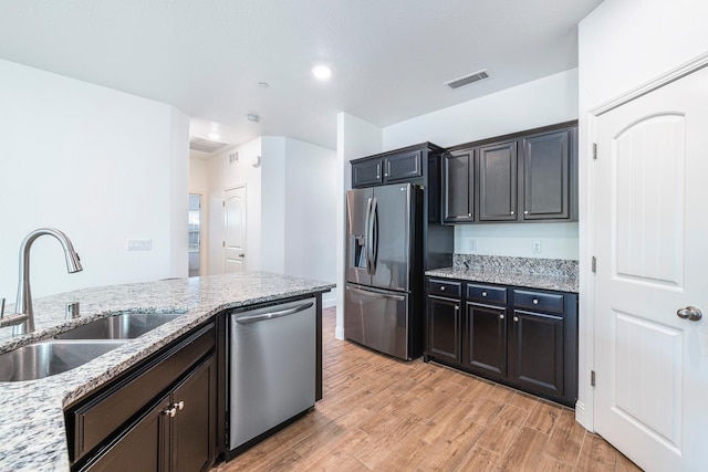 6772 E Ramona Way, Fresno, CA 93727 - kitchen featuring stainless steel appliances, a sink, light wood-type flooring, light stone countertops, and recessed lighting