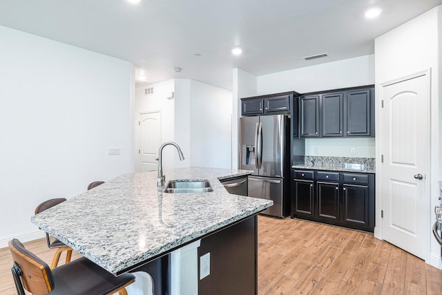 6772 E Ramona Way, Fresno, CA 93727 - kitchen with appliances with stainless steel finishes, a sink, dark cabinetry, a kitchen breakfast bar, and light wood-style floors