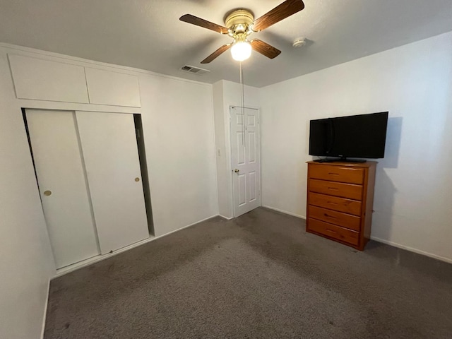 unfurnished bedroom with a closet, dark carpet, a ceiling fan, and baseboards