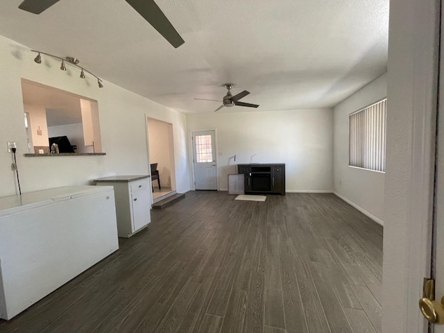 unfurnished living room featuring dark wood finished floors, a ceiling fan, and baseboards