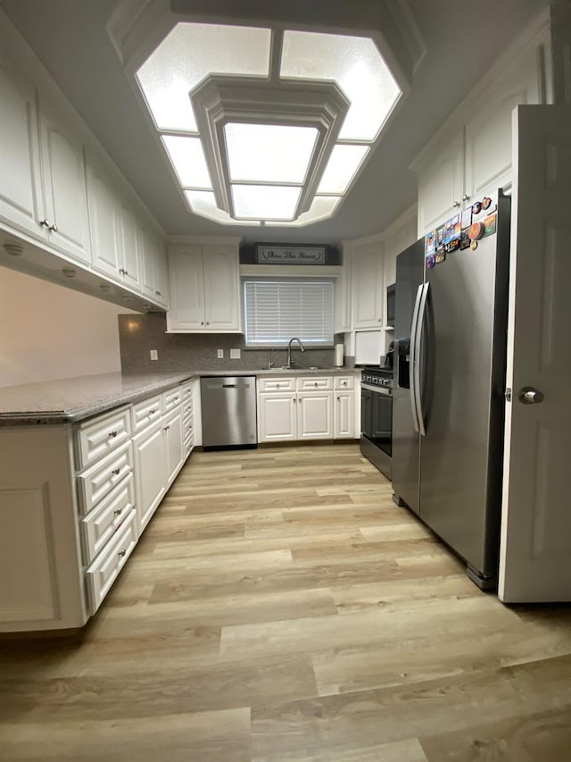 1035 Hoover Way, Hanford, CA 93230 - kitchen featuring appliances with stainless steel finishes, a sink, light wood-type flooring, white cabinets, and decorative backsplash