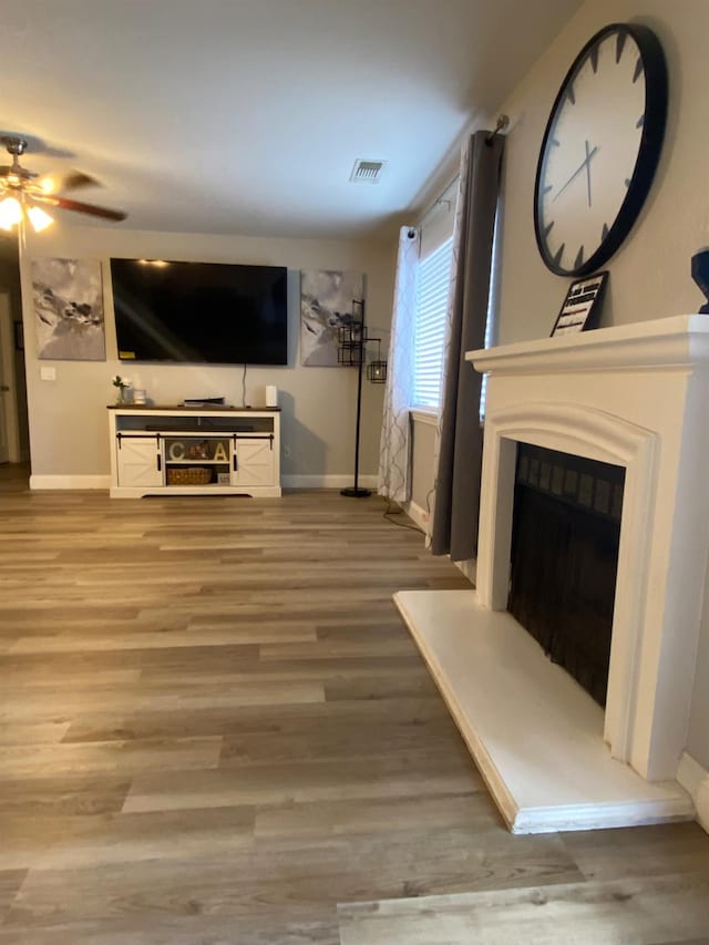 1035 Hoover Way, Hanford, CA 93230 - unfurnished living room featuring baseboards, ceiling fan, wood finished floors, and a fireplace with raised hearth