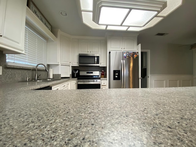 1035 Hoover Way, Hanford, CA 93230 - kitchen with appliances with stainless steel finishes, a sink, white cabinetry, light stone counters, and wainscoting