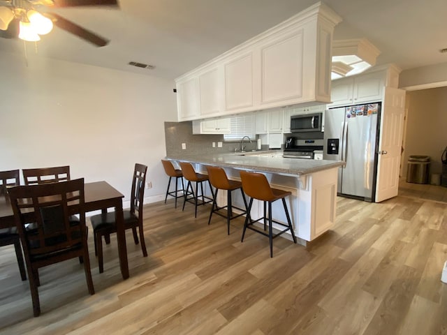 1035 Hoover Way, Hanford, CA 93230 - kitchen with appliances with stainless steel finishes, white cabinets, a peninsula, a sink, and light wood finished floors