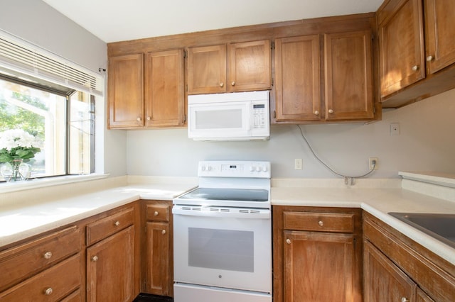 kitchen with white appliances, brown cabinets, light countertops, and a sink