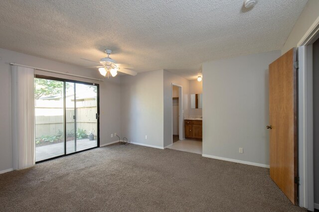 unfurnished bedroom featuring access to exterior, light colored carpet, a textured ceiling, and baseboards