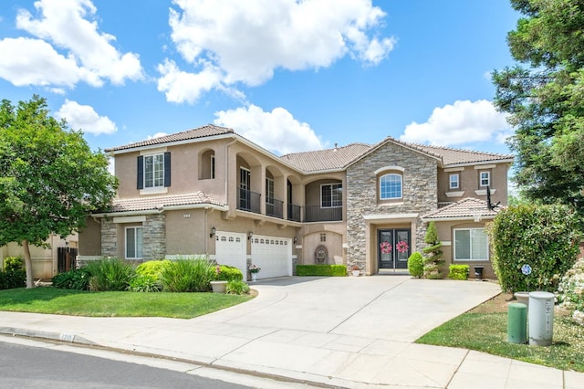 1710 N Filbert Ave, Clovis, CA 93619 - mediterranean / spanish-style house with stone siding, stucco siding, a tile roof, a garage, and french doors