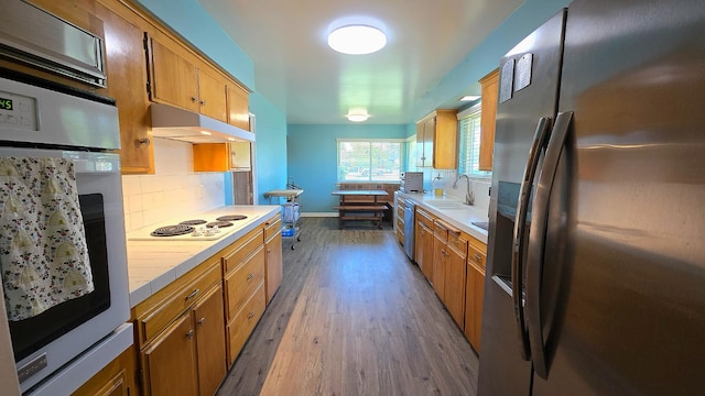 1205 Pine St, Selma, CA 93662 - kitchen with stainless steel appliances, a sink, tile counters, wood finished floors, and backsplash