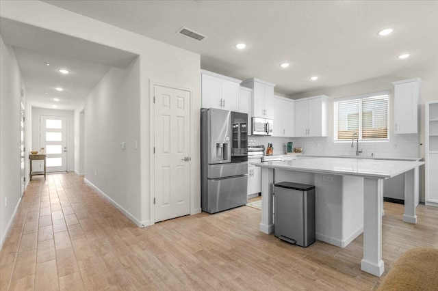 kitchen with stainless steel appliances, decorative backsplash, white cabinets, healthy amount of natural light, and recessed lighting