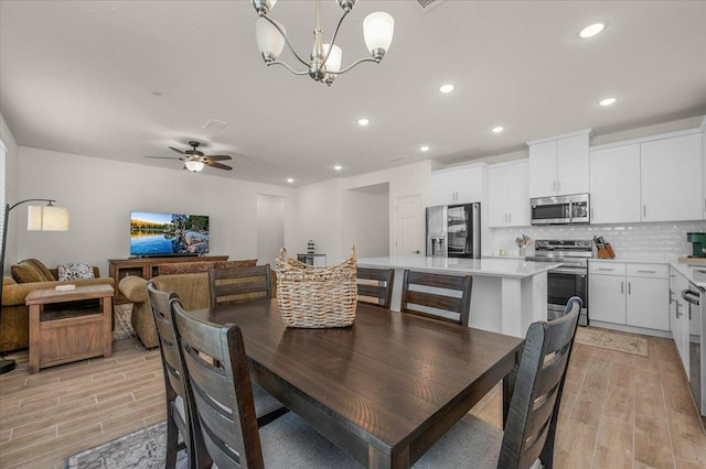 dining space featuring light wood-style floors, recessed lighting, a chandelier, and a ceiling fan