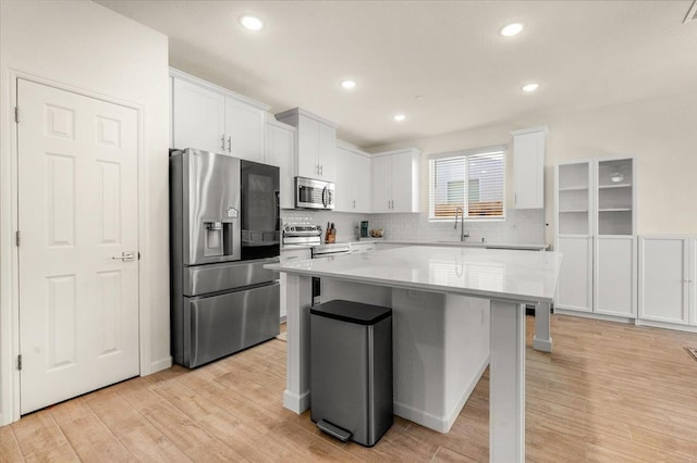 kitchen featuring stainless steel appliances, light wood finished floors, white cabinets, decorative backsplash, and recessed lighting