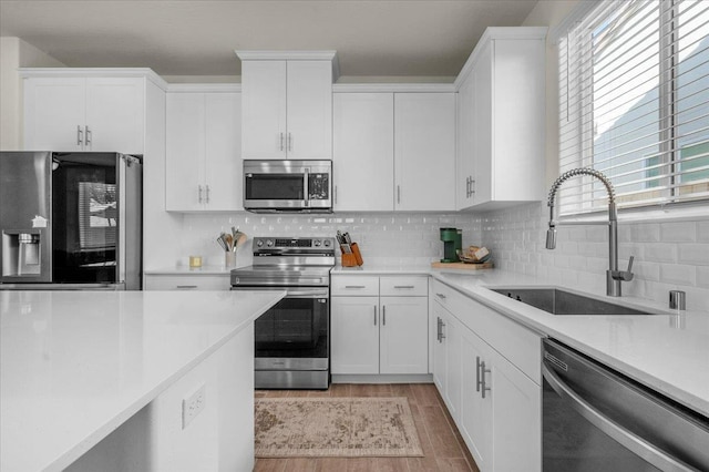 kitchen featuring stainless steel appliances, a sink, white cabinets, and light countertops