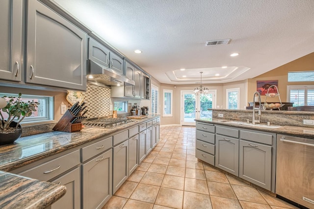 kitchen with stainless steel appliances, gray cabinets, extractor fan, a sink, and a textured ceiling