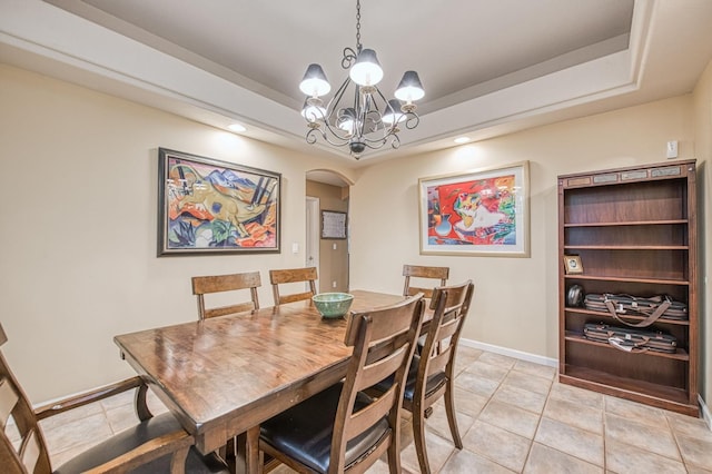 dining space with arched walkways, a raised ceiling, a chandelier, light tile patterned flooring, and baseboards