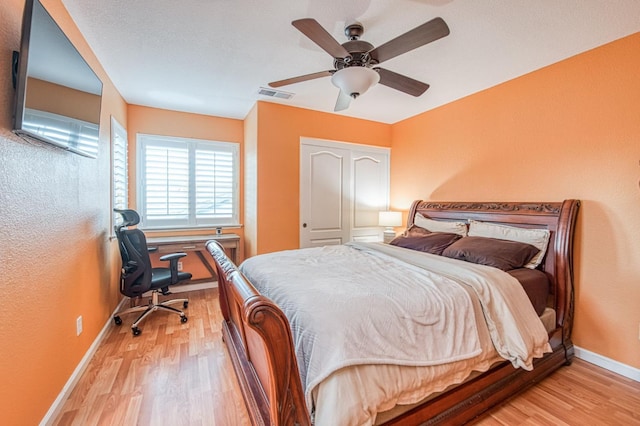 bedroom with baseboards, light wood-style flooring, ceiling fan, and an office area