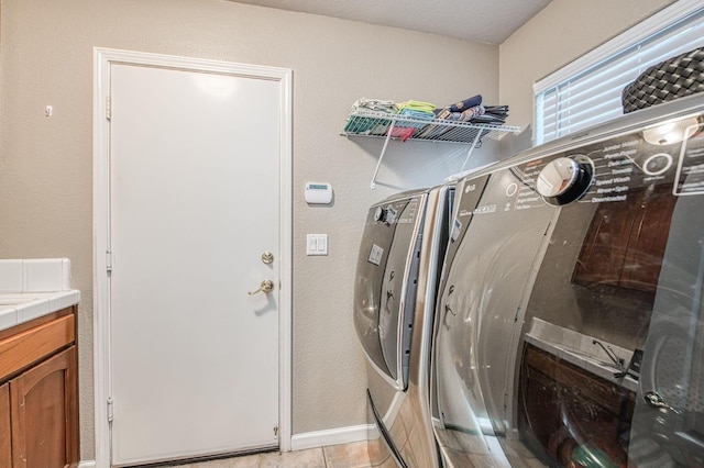 laundry area featuring washing machine and clothes dryer, baseboards, and light tile patterned floors