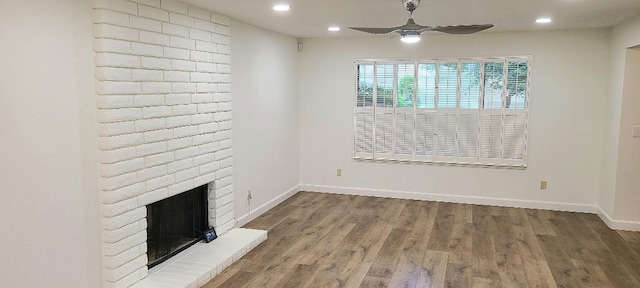 unfurnished living room with a ceiling fan, recessed lighting, wood finished floors, baseboards, and a brick fireplace
