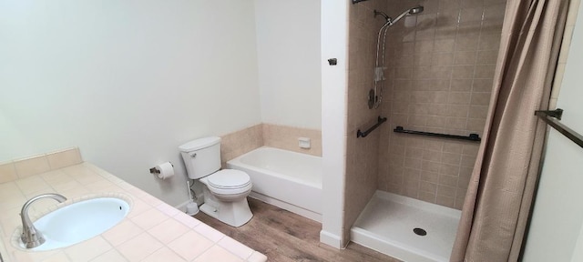 full bath featuring a sink, a tile shower, toilet, and wood finished floors