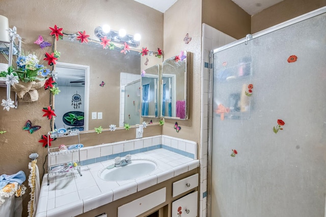bathroom featuring a stall shower, vanity, and a textured wall