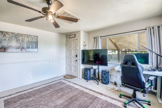 carpeted home office featuring a textured ceiling and ceiling fan