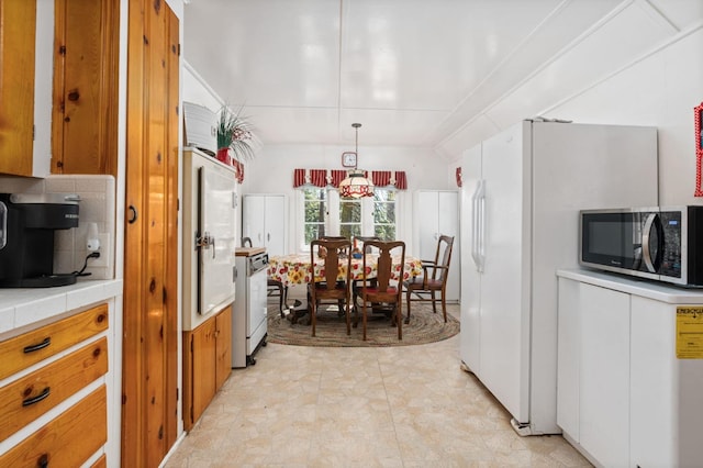 58374 Huntington Lake Rd Unit 12, Lakeshore, CA 93634 - kitchen with stainless steel microwave, tile counters, brown cabinets, tasteful backsplash, and hanging light fixtures