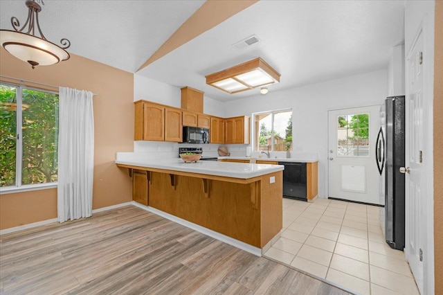 6380 N Cleo, Fresno, CA 93722 - kitchen featuring black appliances, a peninsula, light countertops, light wood finished floors, and a kitchen breakfast bar